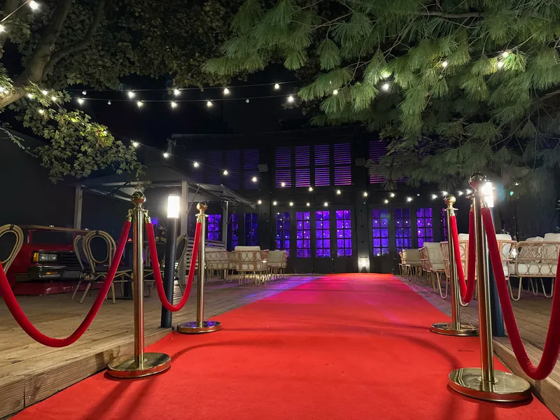 Allée à tapis rouge et cordons dorés devant l'espace lounge de Maya